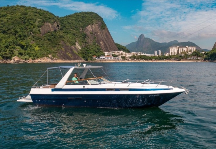 Lancha Favo com casco azul navegando na baía do Rio de Janeiro com montanhas ao fundo